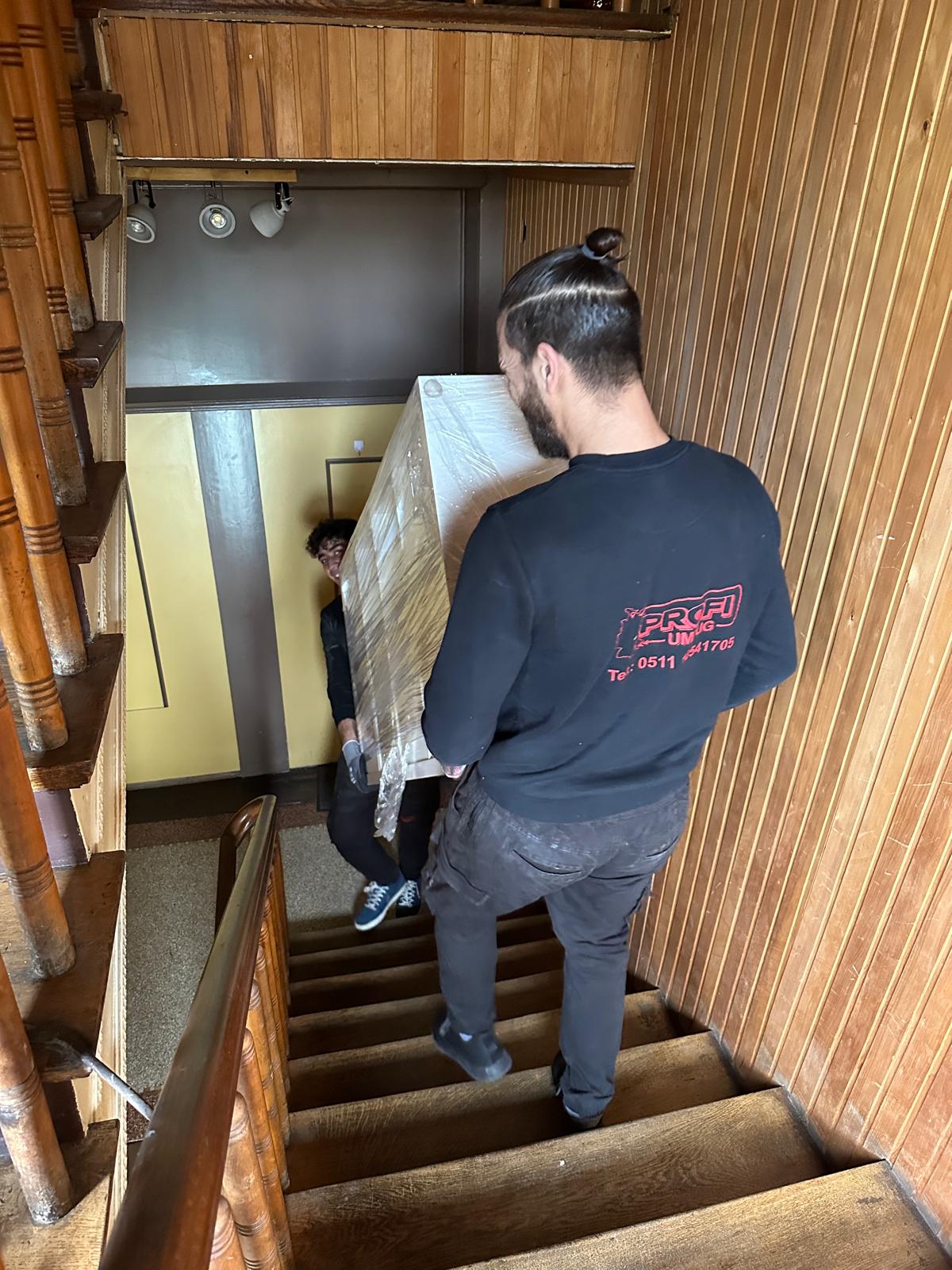 Umzugshelfer trägt Möbel sicher durchs Treppenhaus